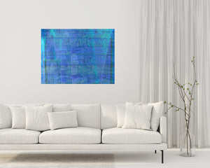 Abstract art has symbols of stones, doors & waves for transformation. Blue art supports serenity, intuition, energy & harmony as wall art in a living room with a sofa.