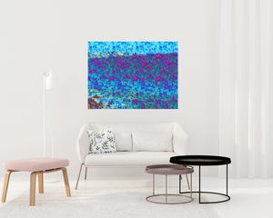 We Are One is an abstract landscape artwork featuring the ocean and trees in blues and some pinks placed on topic of a small sofa in a room.